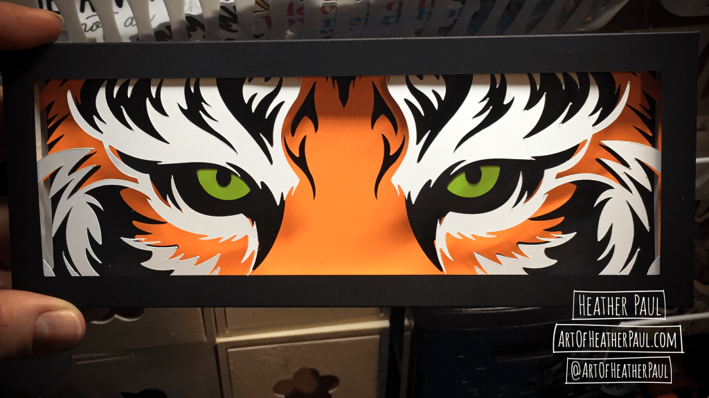 Photo of a shadow box made of layers of cut paper making the image of tiger eyes
